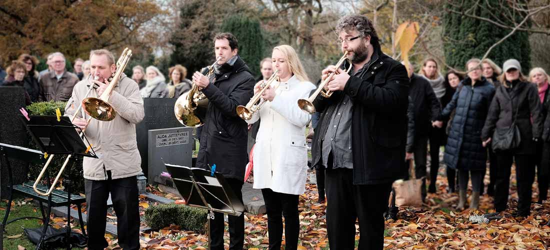 Vier muzikanten spelen bij het graf tijdens een begrafenis op De Nieuwe Ooster in Amsterdam.
